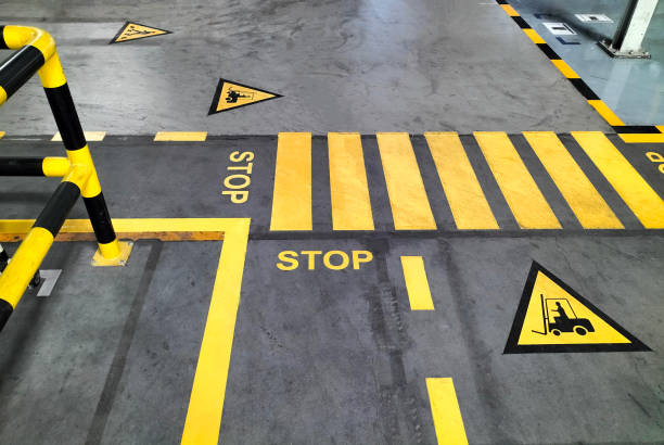 Marquage au sol jaune de sécurité dans un entrepôt, avec bandes STOP, pictogrammes de chariots élévateurs et zones piétonnes